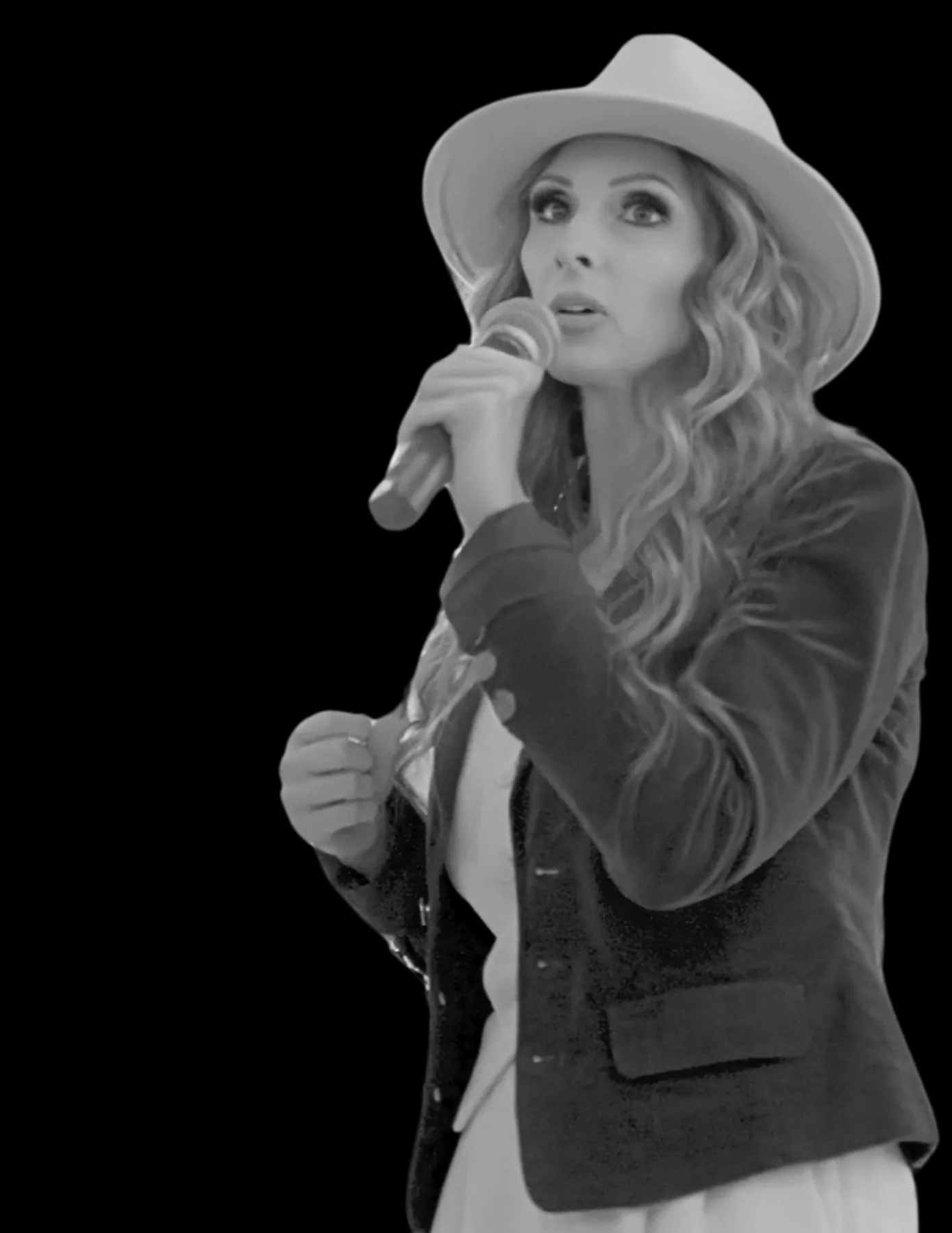 Black and white portrait of Carrie Hill speaking on stage in a white hat